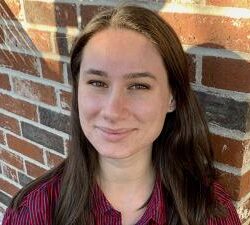 A young white woman with long straight brown hair smiles